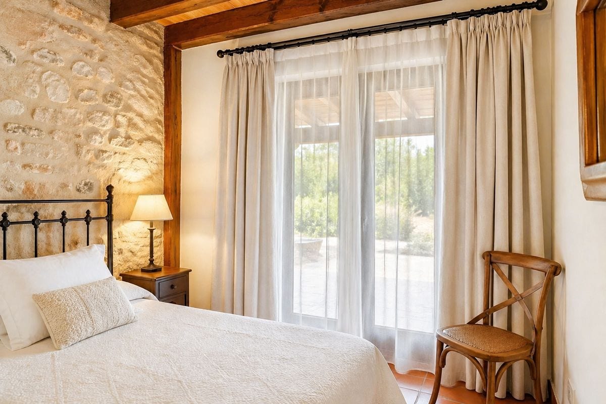 Habitación con ventana grande y cortinas, decorada con estilo rústico y detalles en madera y piedr.